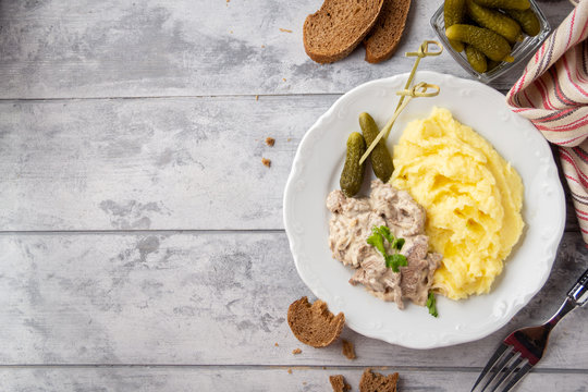 Beef Stroganoff, traditional Russian dish of goulash with beef in creamy sauce, mashed potatoes and pickles. Serve with rustic bread