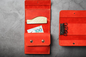 Set of key holder wallet with money and electronic cards and a key holder made of genuine red leather, handmade on a dark background.