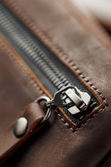 Lock close-up made of brown genuine leather, handmade on a dark background.