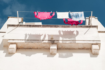 MARTINA FRANCA, ITALY / SEPTEMBER 2019: Clothes drying at the sun in the streets of the old town - obrazy, fototapety, plakaty