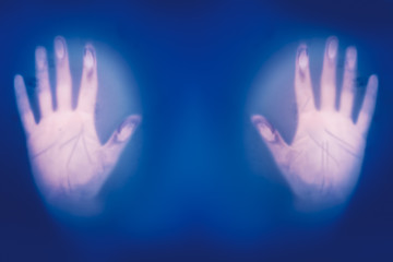 Hands on misted frosted glass, danger and horror of the paranormal, blurred focus