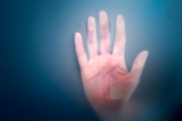 Hand on misted frosted glass, danger and horror of the paranormal, Halloween eve, blurred focus