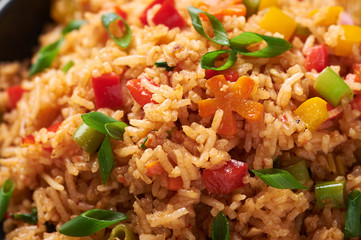Veg Schezwan Fried Rice in black bowl at dark slate background. Vegetarian Szechuan Rice is indo-chinese cuisine dish with bell peppers, green beans, carrot.