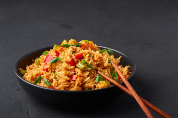 Veg Schezwan Fried Rice in black bowl at dark slate background. Vegetarian Szechuan Rice is...