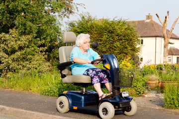 Elderly woman riding on mobility scooter in the sunshine. 