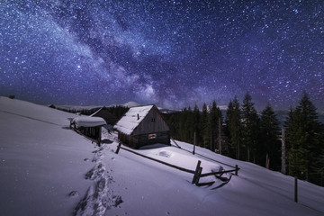 Obraz premium Fairytale landscapes of the winter Carpathian Mountains with a charming milky way in the sky tourist tents and snowy houses in the valleys