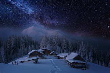Fairytale landscapes of the winter Carpathian Mountains with a charming milky way in the sky tourist tents and snowy houses in the valleys