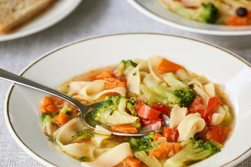 Soup with fresh vegetables and noodles in a white bowl 