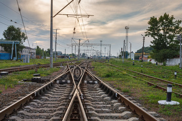 Two railway tracks merge together against beautiful sky at sunset. Industrial landscape with...