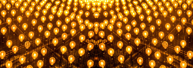 Many light bulbs shining bright. Plenty lightbulbs in rows on ceiling burn, panoramic image