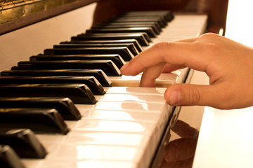 Fototapeta premium The girl's hand on the piano keys. Piano keys background. Selective focus.