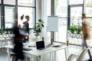 silhouettes of three multiethnic colleagues working and walking in office