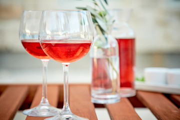 two glasses of rose wine with  olives against blue water on a pier..