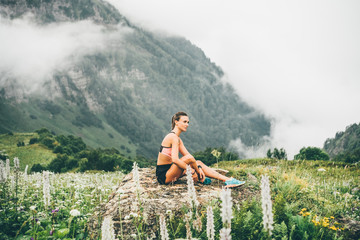 Sport woman relaxing on mountain cliff above the clouds. Alone travel healthy lifestyle. Healthy...