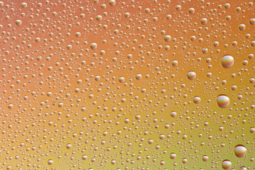 Drops on glass of different sizes and colors on a colored background, texture