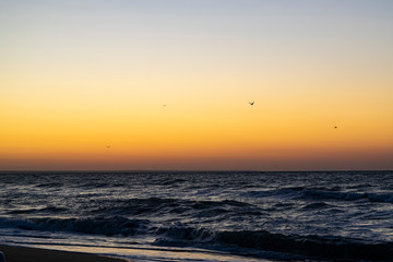 Sunrise over the Black sea, waves on the sandy beach.