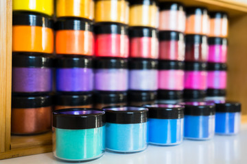 Rainbow color powder in small boxes tins stacked and ordered