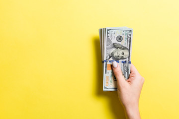Pack of one hundred dollar bills in femle hands with copy space. Top view of money saving concept on colorful background - obrazy, fototapety, plakaty