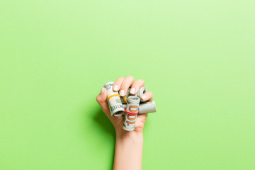 Top view of dollar bills rolled up in tubes in female palm on green background. Retirement concept