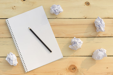 Crumpled paper is scattered on a wooden table. Concept of creative crisis, brainstorming, lack or search for ideas, thoughts, mistakes. Paper in the form of balls. You can place text on paper. Image.