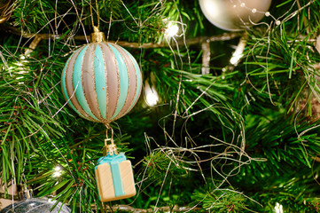 multi-colored Christmas toy in the form of a balloon with a gift hanging on the branches of the holiday tree, along with a garland and other toys