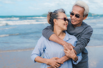 Happy asian couple senior elderly retirement resting at beach honeymoon family together happiness people lifestyle, copy space the left