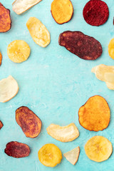 Vegetable chips, healthy vegan snack, an organic food flat lay on a teal blue background, forming a frame with a place for text