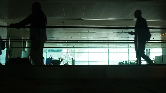 DELHI, INDIA - JUN14, 2018: Silhouette of crowd walking in modern on treadmill India airpot terminal against bright window glass, passengers motion for travel banners, transit airline posters.