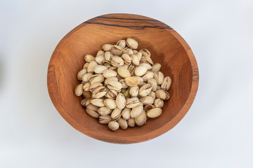 Chestnuts and pistachios in wooden bol as appertiser with drinks against a white background
