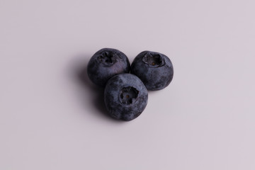 Three juicy round blueberries laying together next to each other with shades view from above