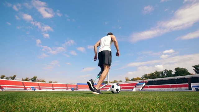 Male player with a bionic leg is practicing with a ball