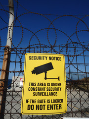 Metal security notice sign on steel barbed wire fence