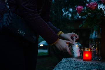 Woman light on red and yellow candles in the dark - to put them on a tombstone - all souls day...