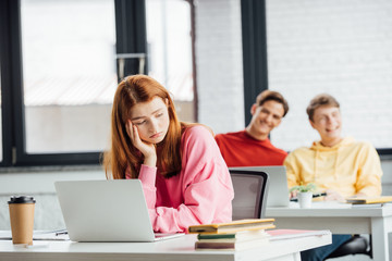sad pensive girl and classmates laughing at her in school