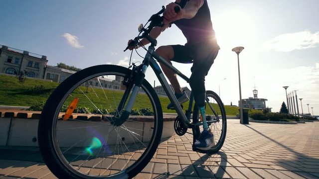 Athlete with a bionic leg is riding a bike along the road