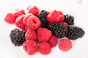 handful of raspberry and blackberry berries on white background