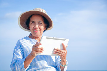 Fototapeta premium Elderly women hold intelligent tablet communication devices for video chatting, talking with their children. Happy retirement concept