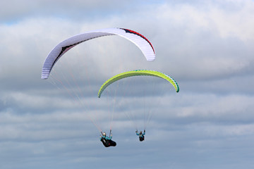 Paragliders flying wings in a cloudy sky