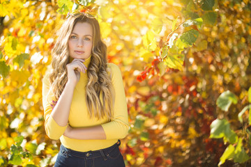 Closeup portrait of attractive young woman on fall background. Beautiful blond female on autumn background outdoors.