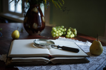 Old books on a wooden table and glass magnifier.