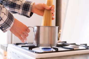 hands put the bunch of spaghetti pasta in the cooking  pan in the kitchen