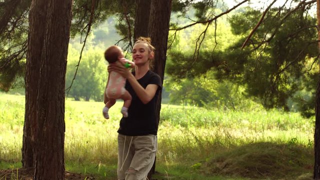young Mom plays with a little baby girl in the woods