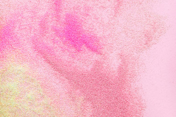 Many multi-colored spangles are scattered on a pink background. View from above. Place for text.