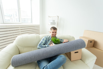 Positive young man sitting on the sofa with his things in the new living room after the move....