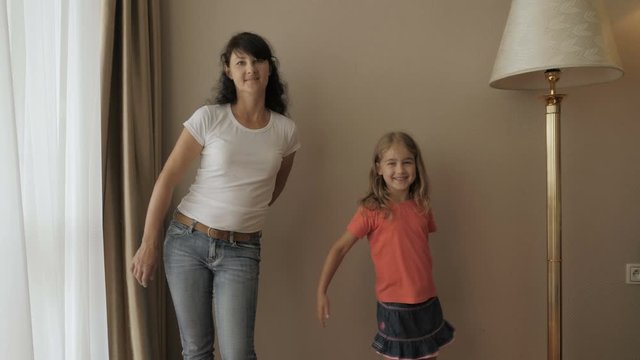 Happy Little Girl And Women Dancing Have Fun In Room. Happy Family Of Cute Daughter And Young Mother Jumping Dancing At Home. Floss Dance Viral. Mother Her Daughter Playing At A Living Room.