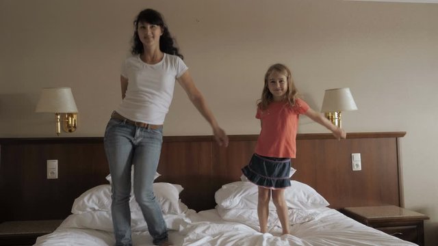 Happy Little Girl And Women Dancing Have Fun In Bedroom. Happy Family Of Cute Daughter And Young Mother Jumping Dancing On Bed At Home. Floss Dance Viral. Mother Her Daughter Playing At A Bedroom.