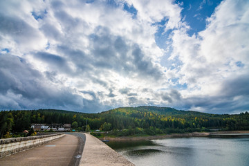 The Schwarzenbachtalsperre in Black Forest, Germany, with many clouds and some colored trees in the fall. 