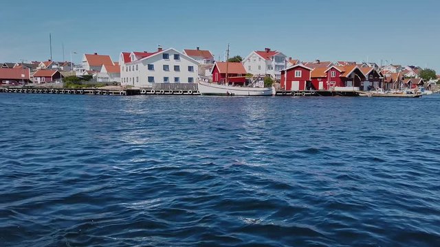 Red and white wooden boathouses in the port of Kungshamn, a small fishing village on the west coast of Sweden