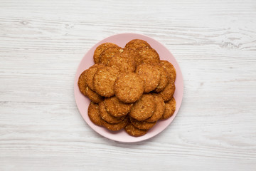 Cereal cookies on a pink plate on a white wooden surface, top view. Flat lay, overhead, from above. Close-up.