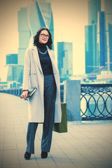 Beautiful smiling woman in a light trendy coat on the waterfront